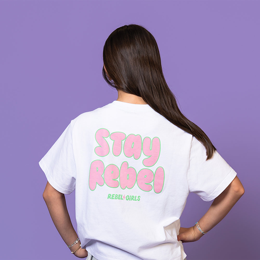 Girl wearing a white tee with "Stay Rebel" text in pink and green